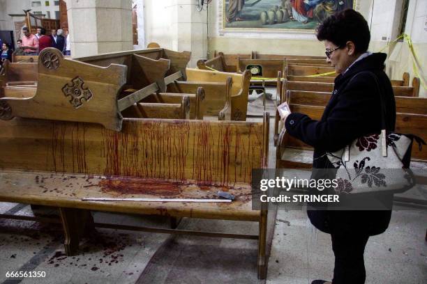 Graphic content / TOPSHOT - An Egyptian woman uses her cell phone to take pictures of the destruction, debris, and bloodstains inside the Mar Girgis...