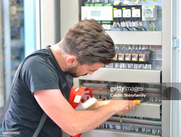 knappe elektricien werken met werk hulpmiddel op elektrische kamer - fuse box stockfoto's en -beelden