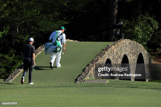 Justin Rose of England walks over the Hogan Bridge with his caddie Mark Fulcher during the final round of the 2017 Masters Tournament at Augusta...