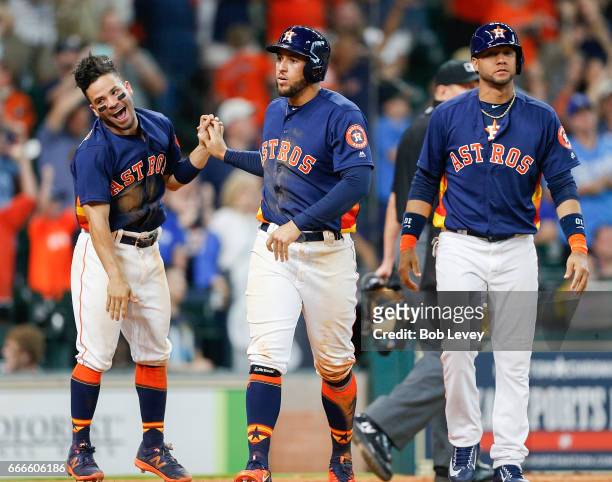 George Springer of the Houston Astros celebrates with Jose Altuve and Yuli Gurriel after scoring on a walk in the second inning against the Kansas...