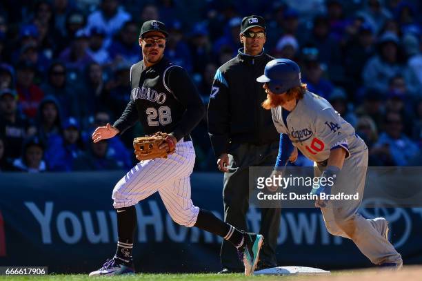 Justin Turner of the Los Angeles Dodgers turns to run and score after an error on a pickoff attempt as Nolan Arenado of the Colorado Rockies looks on...