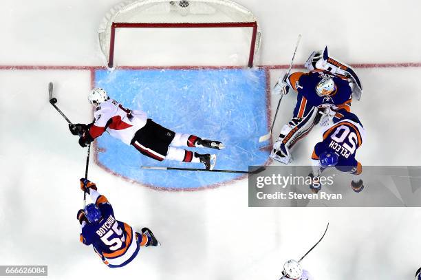 Bobby Ryan of the Ottawa Senators attempts a shot on goal as he falls to the ice as Thomas Greiss of the New York Islanders tends to net and Johnny...