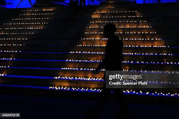 Man walks by candles on the stairs of Brooklyn's Borough Hall during a protest against President Donald Trump's immigration policies on April 9, 2017...