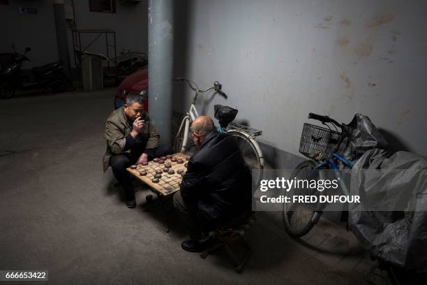 This picture taken on March 22, 2017 shows men playing Chinese chess in a hutong in Beijing. With space scarce in the city of 21.5 million, most...