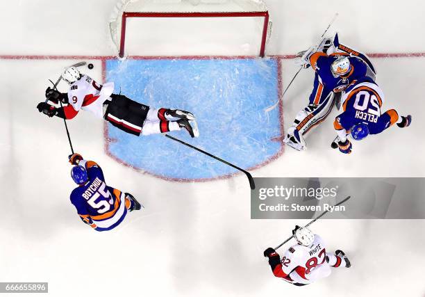 Bobby Ryan of the Ottawa Senators attempts a shot on goal as he falls to the ice as Thomas Greiss of the New York Islanders tends to net and Johnny...