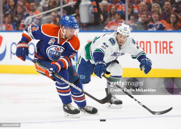 Andrej Sekera of the Edmonton Oilers keeps the puck away from Michael Chaput of the Vancouver Canucks on April 9, 2017 at Rogers Place in Edmonton,...