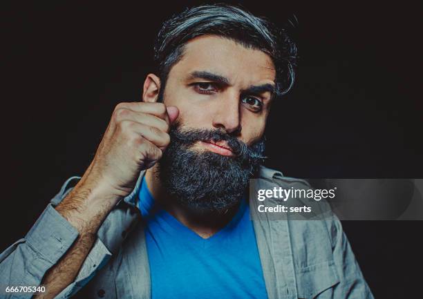 portret van jonge bebaarde man draaien zijn snor. - middle east cool stockfoto's en -beelden