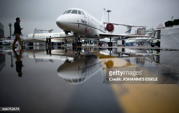 Man passes the Dassault Falcon 2000EX business jet before the start of the 2017 Asian Business Aviation Conference and Exhibition at Shanghai's...