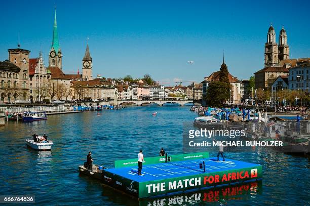 Swiss tennis superstar Roger Federer serves a ball to world number one Britain's Andy Murray during a promotion on a raft on the river Limmat before...