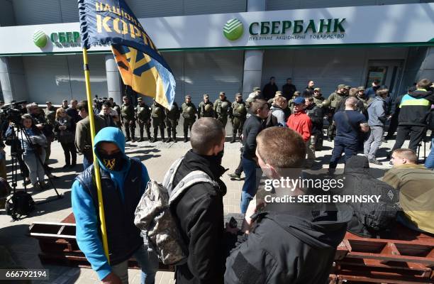 Activists protest in front of Ukrainian National Guard soldiers guarding the Russian owned Sberbank Bank in Kiev on April 10, 2017. Ukrainian...