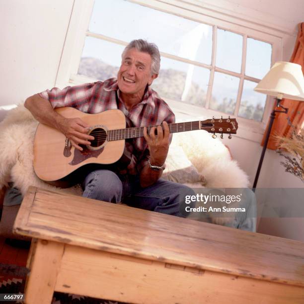 Austrailian-born actor George Lazenby plays his guitar at home November 1, 1999 in Valyermo, Ca. Thirty years after his rocky one-time outing as...