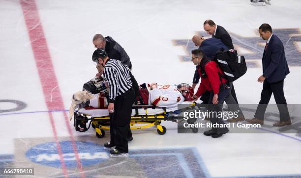 Tariq Hammond of the Denver Pioneers is taken off the ice on a stretcher after he crashed into the boards breaking his ankle during the 2017 NCAA...