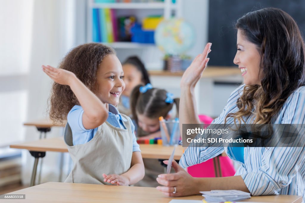 Proud teacher gives student a high five in math class