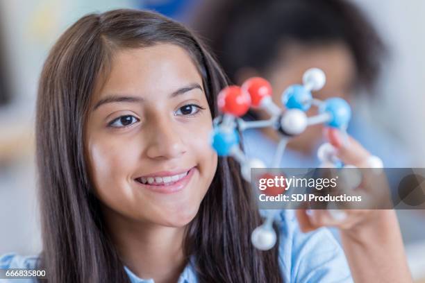 confident hispanic junior high student examines molecular structure - long term disability stock pictures, royalty-free photos & images