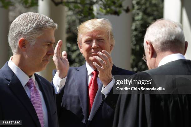 President Donald Trump applauds after Supreme Court Associate Justice Neil Gorsuch took the judicial oath during a ceremony in the Rose Garden at the...
