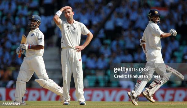 Indian batsmen Rahul Dravid and MS Dhoni take a run as New Zealand bowler Andy McKay looks in disgust on the second day of the third test match...