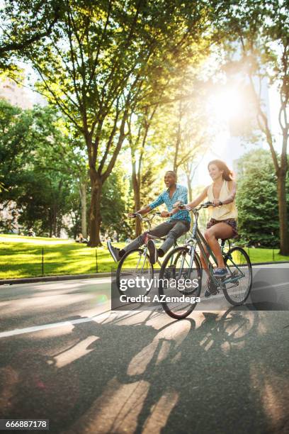 fahrradfahren im central park - fun couple on bike stock-fotos und bilder