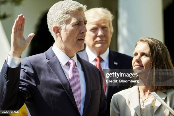 Judge Neil Gorsuch, left, recites the oath of office as his wife Louise Gorsuch and U.S. Donald President Trump listen during the swearing in...