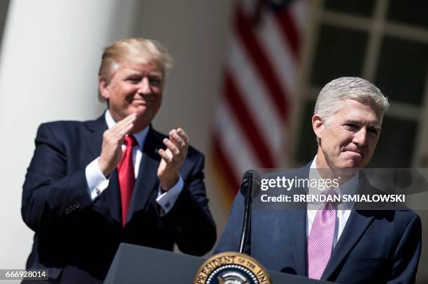 President Donald Trump claps for Neil Gorsuch after he took the judicial oath during a ceremony in the Rose Garden of the White House April 10, 2017...