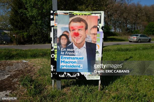 Picture taken on April 10, 2017 shows a billboard with the campaign poster of French presidential election candidate for the En Marche ! movement...