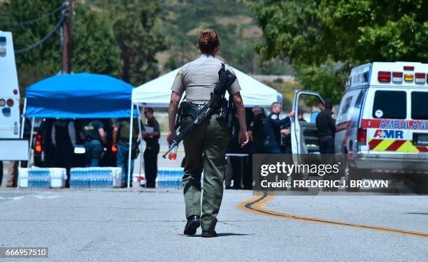 An armed law enforcement personnel walks outside a closed-off North Park Elementary School in San Bernardino, California on April 10 following a...