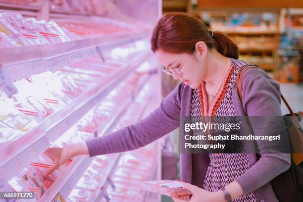 woman reading label on the pack at supermarket - suphat bhandharangsri stock pictures, royalty-free photos & images