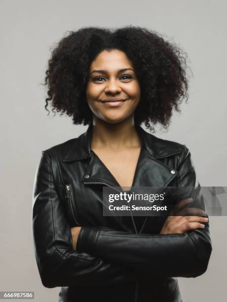 mooie afrikaanse vrouw die lacht met haar gekruiste armen - leather jacket stockfoto's en -beelden