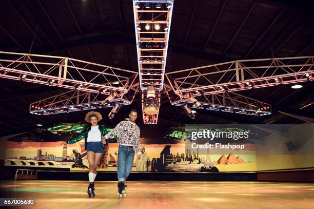 couple having fun at roller disco - patín de ruedas fotografías e imágenes de stock