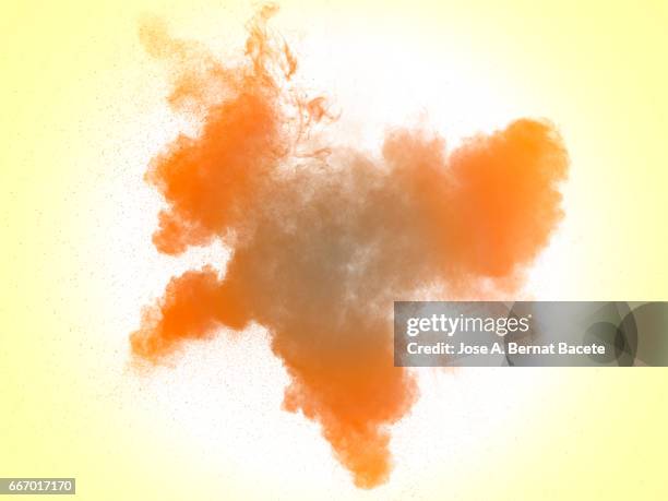 explosion of a cloud of powder of particles of  colors yellow and orange on a white background - partícula stock-fotos und bilder