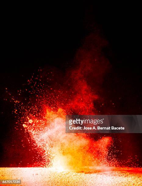 explosion of a cloud of powder of particles of orange and yellow color on a black background - etéreo stockfoto's en -beelden