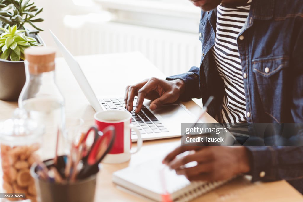 Junger Mann am Laptop arbeiten und Notizen