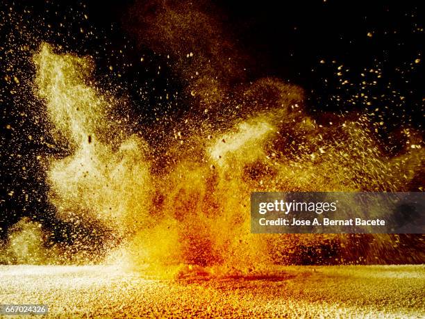 explosion of a cloud of powder of particles of orange and yellow color on a black background - dust storm stock pictures, royalty-free photos & images