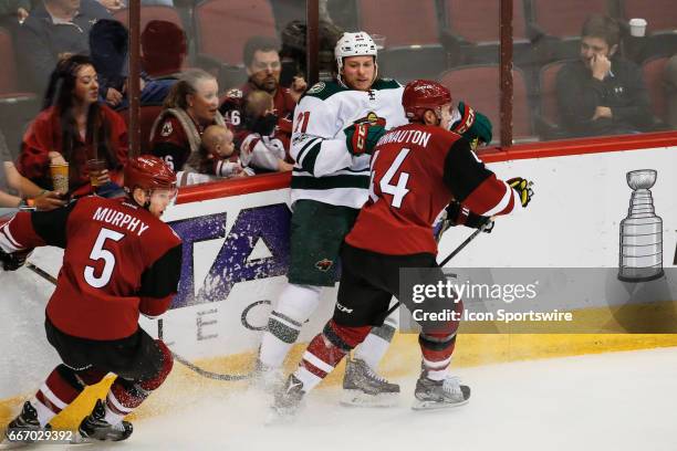 Minnesota Wild center Ryan White is checked by Arizona Coyotes defenseman Kevin Connauton during the NHL hockey game between the Minnesota Wild and...