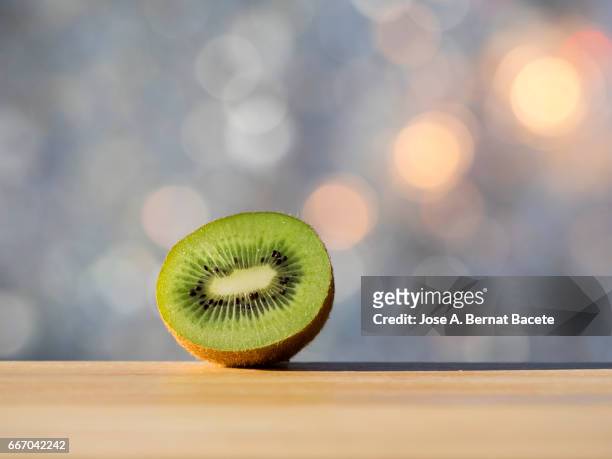 split kiwi fruit in half, illuminated by the light of the sun - frescura stockfoto's en -beelden