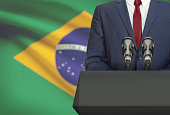 Businessman or politician making speech from behind a pulpit with national flag on background - Brazil
