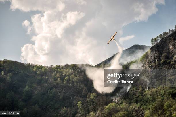 firefighter airplane putting out a fire on mountain forest - airplane fire stock pictures, royalty-free photos & images