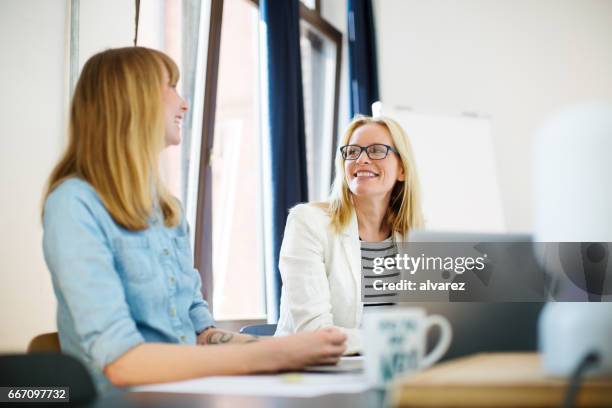 kreative unternehmerinnen diskutieren im büro - two people talking face to face stock-fotos und bilder