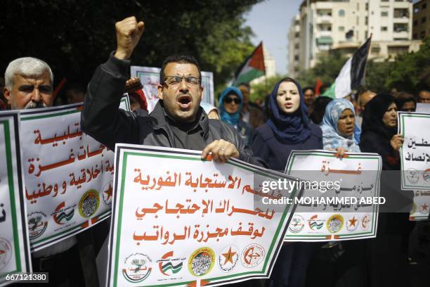 Palestinians shout slogans and hold placards during a protest in Gaza City on April 10, 2017 against a decision by the West Bank-based Palestinian...