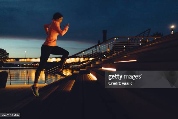 young woman jogging at night on riverside - running lights stock pictures, royalty-free photos & images