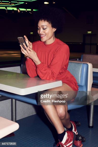 woman using her phone at roller disco - roller rink stock-fotos und bilder
