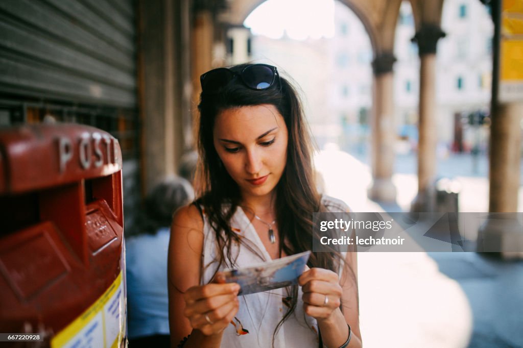 Portrait of a young brunette in Trieste, Italy writing a postcard