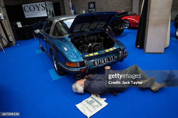 Man looks underneath a 1973 Porsche 911 Targa at the Royal Horticultural Halls on April 11, 2017 in London, England. Coys automobile auctioneers are...