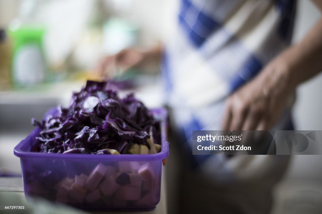 Woman in kitchen chopping vegetables