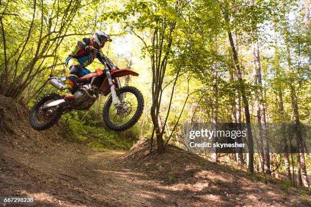 motocross rider jumping on extreme terrain in the woods. - motorcross stock pictures, royalty-free photos & images