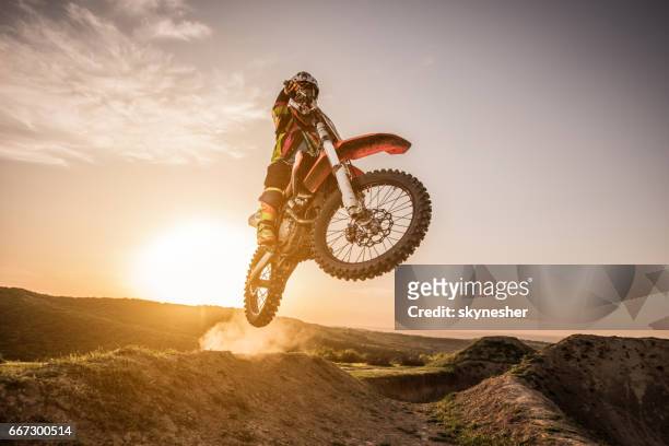 motocross rider jumping over dirt hills at sunset. - corrida de motos imagens e fotografias de stock