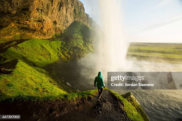 a woman watching sunset near a waterfall. - reykjavik stockfoto's en -beelden