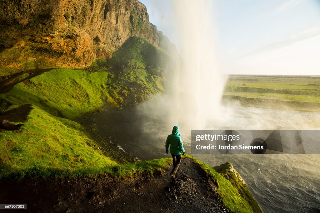 A woman watching sunset near a waterfall.