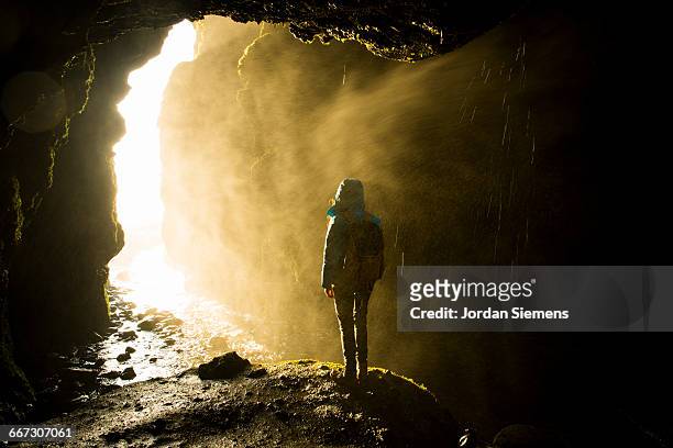 a woman standing in a wet cave. - cave stock pictures, royalty-free photos & images