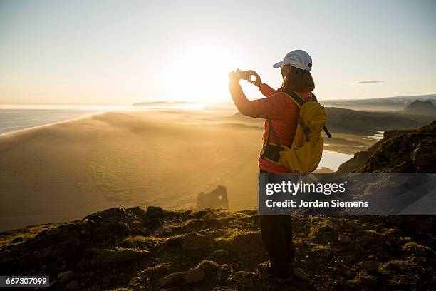 a hiker on a cliff watching sunset - reykjavik women stock pictures, royalty-free photos & images