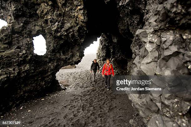 a couple hiking a beach. - black sand iceland stock pictures, royalty-free photos & images